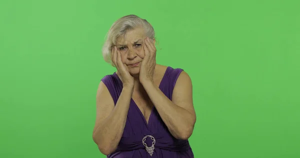 Μια ηλικιωμένη γυναίκα υποφέρει από προβλήματα πόνου στον πονοκέφαλο. Η γριά γιαγιά. Πλήκτρο αποχρώσεων — Φωτογραφία Αρχείου