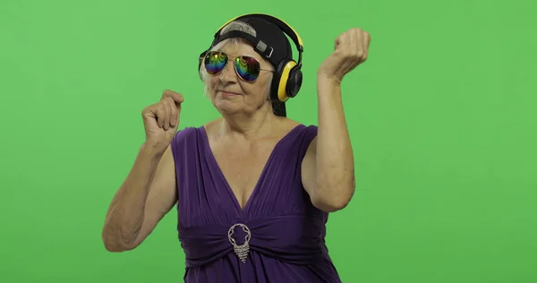 Mujer mayor escucha música en auriculares y bailes. Abuela. Clave de croma —  Fotos de Stock