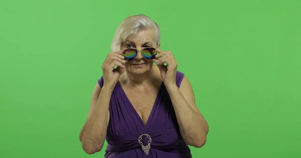 Una anciana con gafas de sol sonríe. Vieja abuela. Clave de croma — Foto de Stock