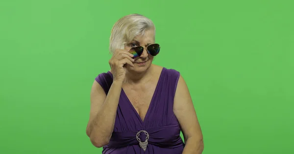 Una anciana con gafas de sol sonríe. Vieja abuela. Clave de croma — Foto de Stock