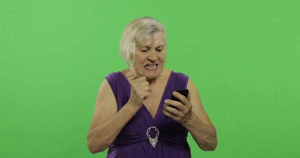 Starsza agresywna kobieta działa na smartfonie. Stara babcia. Klucz chrominancji — Zdjęcie stockowe