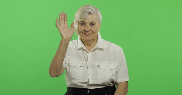 Uma mulher idosa acenando para a câmera e sorri. Velha avó. Chave Chroma — Fotografia de Stock