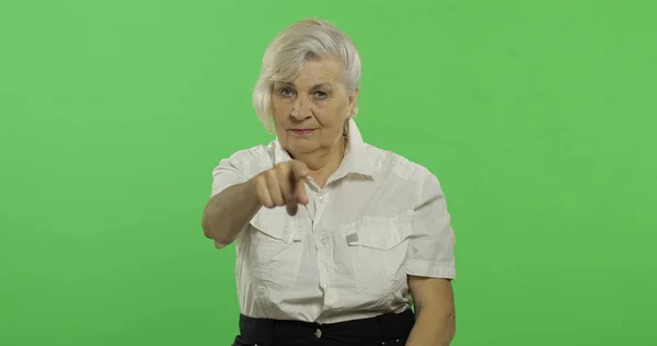 En äldre kvinna pekar på kameran och ler. Gamla farmor. Chroma Key — Stockfoto
