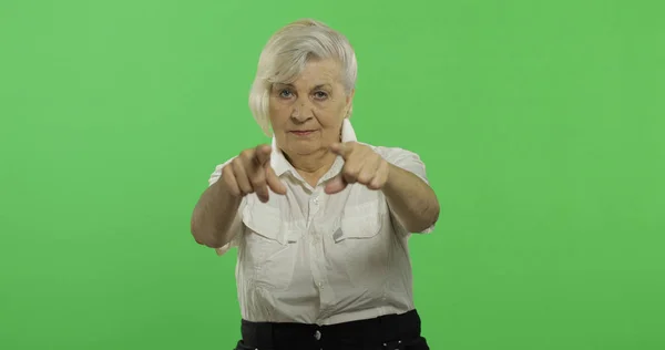 Uma mulher idosa aponta para a câmera e sorri. Velha avó. Chave Chroma — Fotografia de Stock