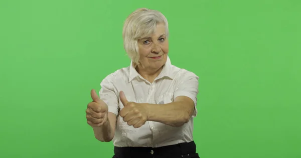 Une femme âgée lève le pouce et sourit. Vieille grand-mère. Clé chromatique — Photo