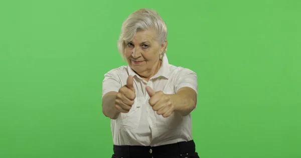 Une femme âgée lève le pouce et sourit. Vieille grand-mère. Clé chromatique — Photo