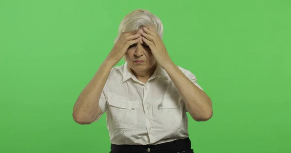 Una donna anziana soffre di mal di testa. Vecchia nonna. Chiave cromatica — Foto Stock