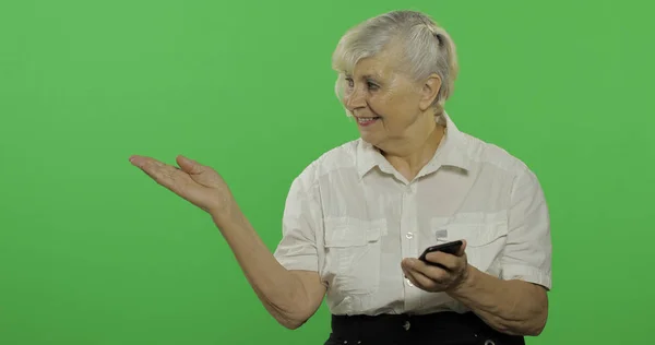 An elderly woman adjusts her clothes and smiles. Chroma key — Stock Photo, Image