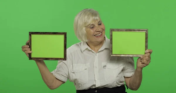 Starsza kobieta trzyma dwie klatki z zielonym obrazem. Babcia. Klucz chrominancji — Zdjęcie stockowe
