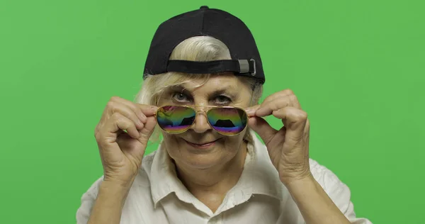 En äldre kvinna i solglasögon och mössa ler. Gamla farmor. Chroma Key — Stockfoto