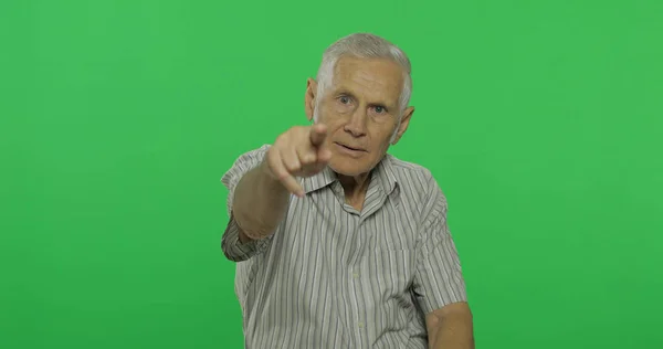 O senhor aponta para a câmara. Bonito homem velho no fundo da chave chroma — Fotografia de Stock