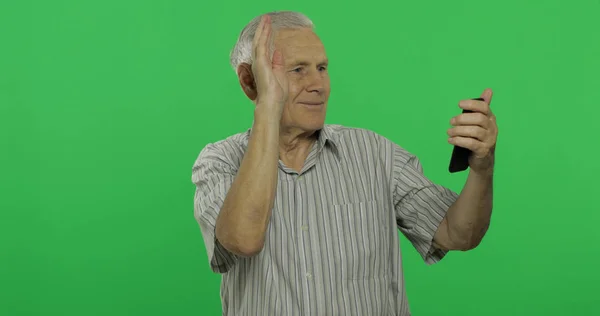 Hombre mayor habla en un teléfono inteligente. Hombre viejo guapo en croma clave fondo — Foto de Stock