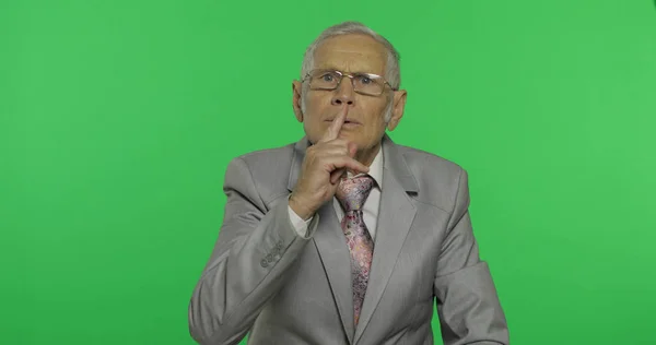 Un hombre de negocios mayor mostrando un gesto de silencio. Hombre mayor mostrando gesto shh — Foto de Stock