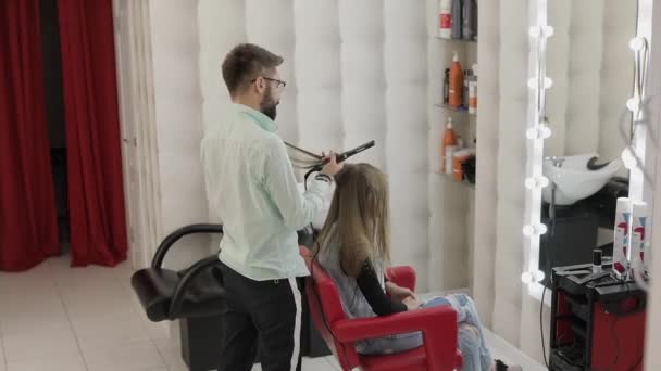 Peluquería profesional que trabaja con el cabello modelo. Enderezamiento de hierro corrugado — Vídeos de Stock