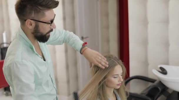 Профессиональный парикмахер расчесывает волосы модели. Создание объемной прически — стоковое видео