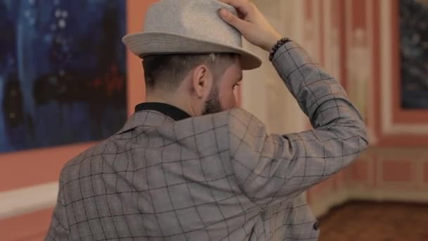 Face attractive stylish young bearded man in hat returns and looks at camera — Stock Video