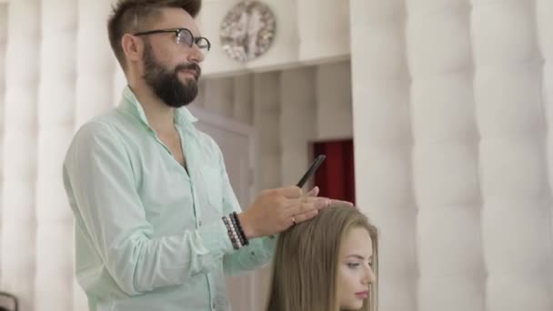 Профессиональный парикмахер расчесывает волосы модели. Создание объемной прически — стоковое видео