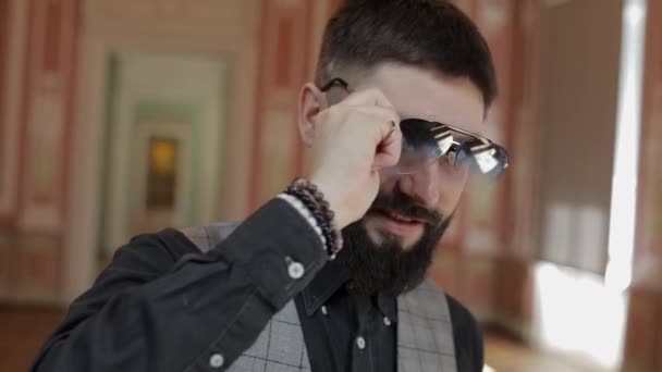 Cara atractiva hombre barbudo con estilo quitando gafas de sol. Guapo chico sonriendo — Vídeos de Stock