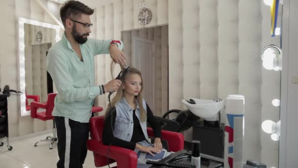 Profesjonalny Fryzjer pracujący z modelowymi włosami. Prostowanie żelaza falistego — Wideo stockowe