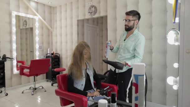 Professionele kapper styling blaast lak op model haar met een haardroger — Stockvideo