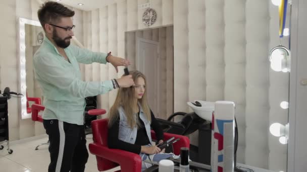Профессиональный парикмахер расчесывает волосы модели. Красивая женщина в салоне — стоковое видео
