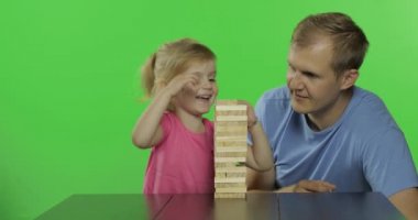 Baba ve kızı jenga oynar. Küçük çocuk kuleden ahşap bloklar çeker