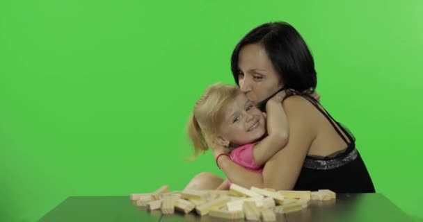 母と娘はジェンガを演じます。木製のブロックから塔を作る子供 — ストック動画