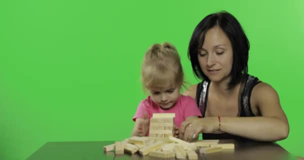 Madre e hija tocan la jenga. Niño haciendo una torre de bloques de madera — Vídeos de Stock