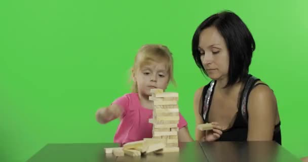 Madre e hija tocan la jenga. Niño haciendo una torre de bloques de madera — Vídeos de Stock