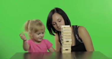 Anne ve kızı jenga oynar. Çocuk kuleden ahşap bloklar çeker