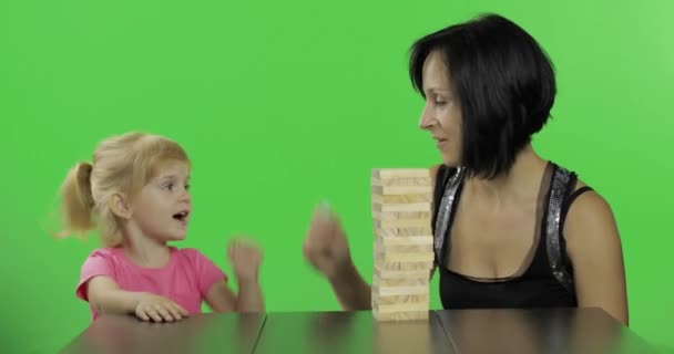 A mãe e a filha fazem de jenga. Criança puxa blocos de madeira da torre — Vídeo de Stock