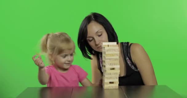 Madre e figlia suonano la jenga. Bambino tira blocchi di legno dalla torre — Video Stock