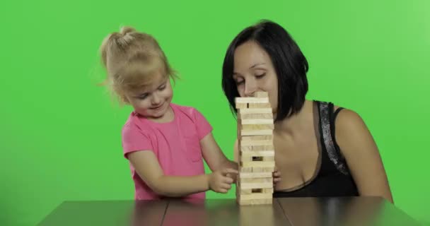 Moeder en dochter spelen de Jenga. Kind trekt houten blokken van de toren — Stockvideo