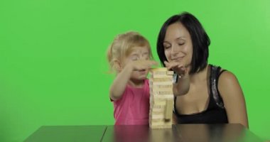Anne ve kızı jenga oynar. Ahşap bloklardan kule yapan çocuk