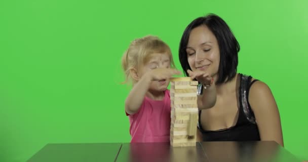 母と娘はジェンガを演じます。木製のブロックから塔を作る子供 — ストック動画