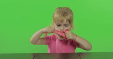 Mutlu küçük kız kroma anahtar arka plan üzerinde plasticine ile oynar