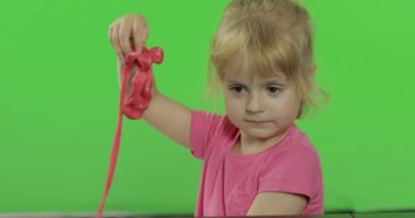 Mutlu küçük kız kroma anahtar arka plan üzerinde plasticine ile oynar