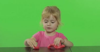 Mutlu küçük kız kroma anahtar arka plan üzerinde plasticine ile oynar