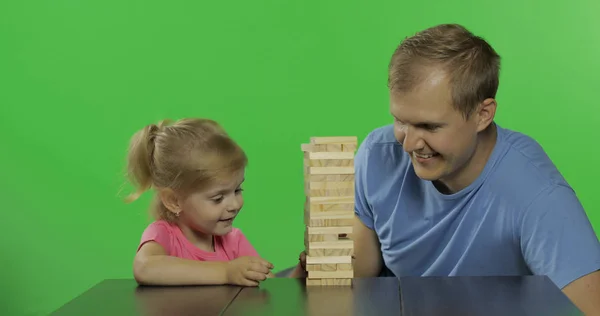 Vader en dochter spelen de Jenga. Kleine kind trekt houten blokken van de toren — Stockfoto