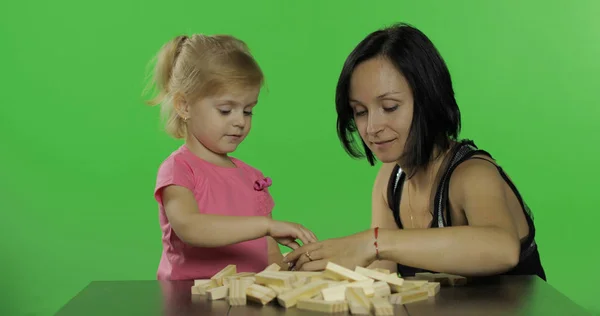 Moeder en dochter spelen de Jenga. Kind maken van een toren uit houten blokken — Stockfoto