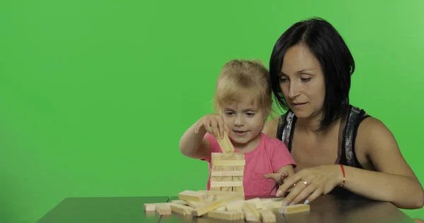 Moeder en dochter spelen de Jenga. Kind maken van een toren uit houten blokken — Stockfoto