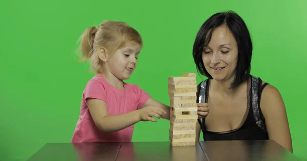 Moeder en dochter spelen de Jenga. Kind trekt houten blokken van de toren — Stockfoto