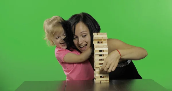 Moeder en dochter spelen de Jenga. Kind trekt houten blokken van de toren — Stockfoto