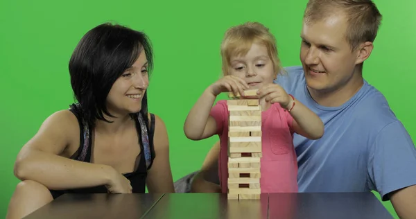 Moeder, vader en dochter spelen jenga. Trekt houten blokken van de toren — Stockfoto