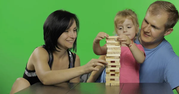 Moeder, vader en dochter spelen jenga. Trekt houten blokken van de toren — Stockfoto