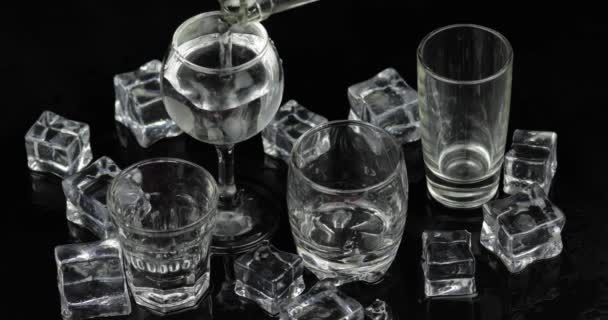 Het gieten van foto's van wodka van een fles in drinkglas. Zwarte achtergrond — Stockvideo