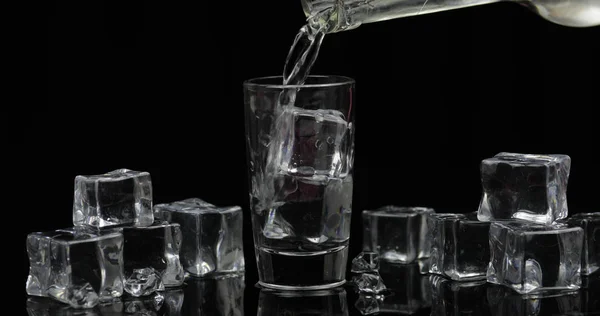 Wodka aus einer Flasche ins Glas gießen. schwarzer Hintergrund — Stockfoto