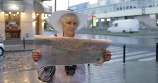 Старша жінка-туристка, яка досліджує місто з картою в руках. Шукаю маршрут — стокове відео
