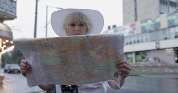 Senior kvinnlig turist utforska staden med en karta i händerna. Letar du efter rutten — Stockvideo