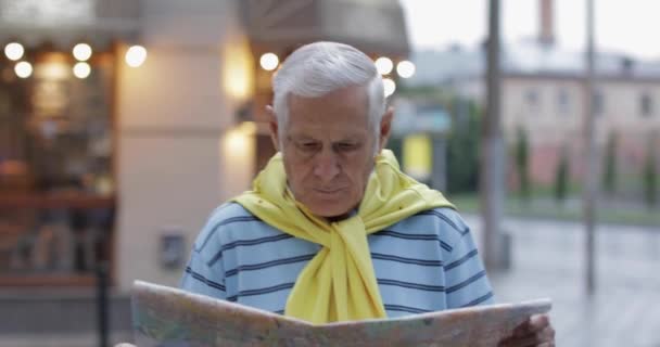 Senior mannelijke toerist verkennen stad met een kaart in handen en op zoek naar de route — Stockvideo